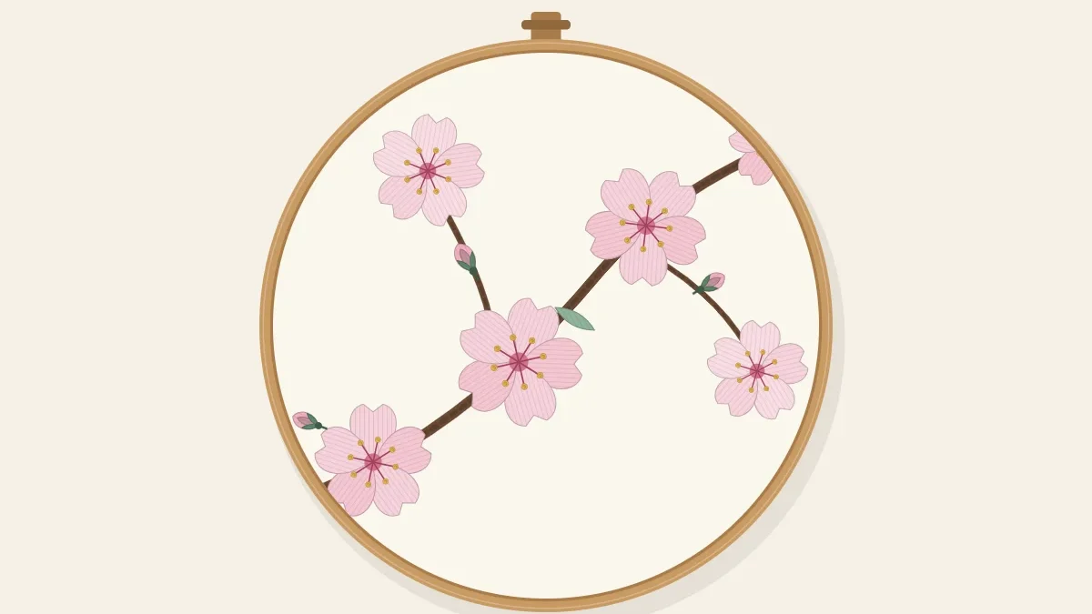 A brown branch with pale pink cherry blossoms and buds, stitched inside an embroidery hoop